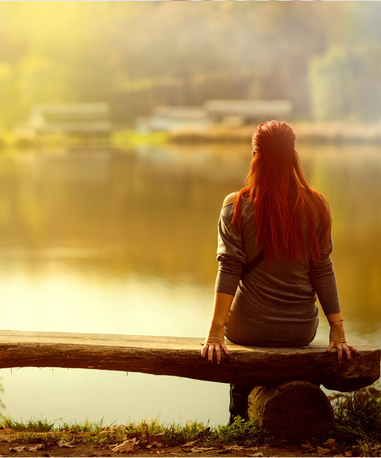 woman sitting on bench by water thinking