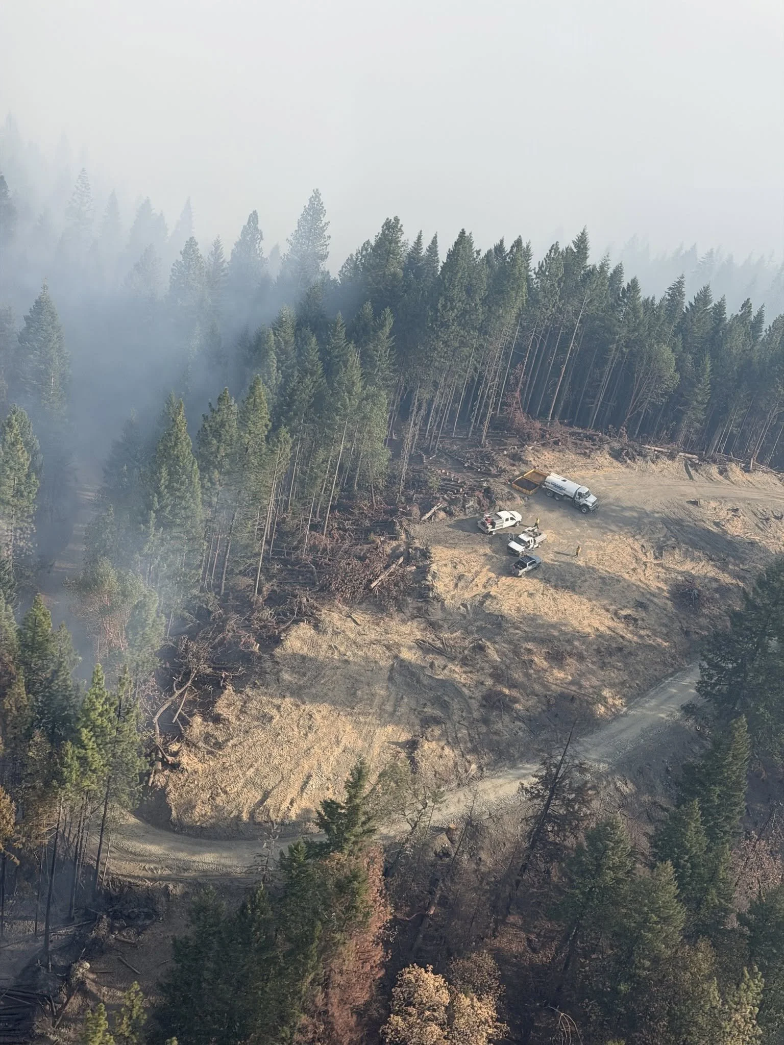   Suppression Operations:  Fire resources are positioned along a cleared area near the West Fork Evans Creek Fire as smoke lingers over surrounding timber.  Oregon Department of Forestry Southwest Oregon District.  