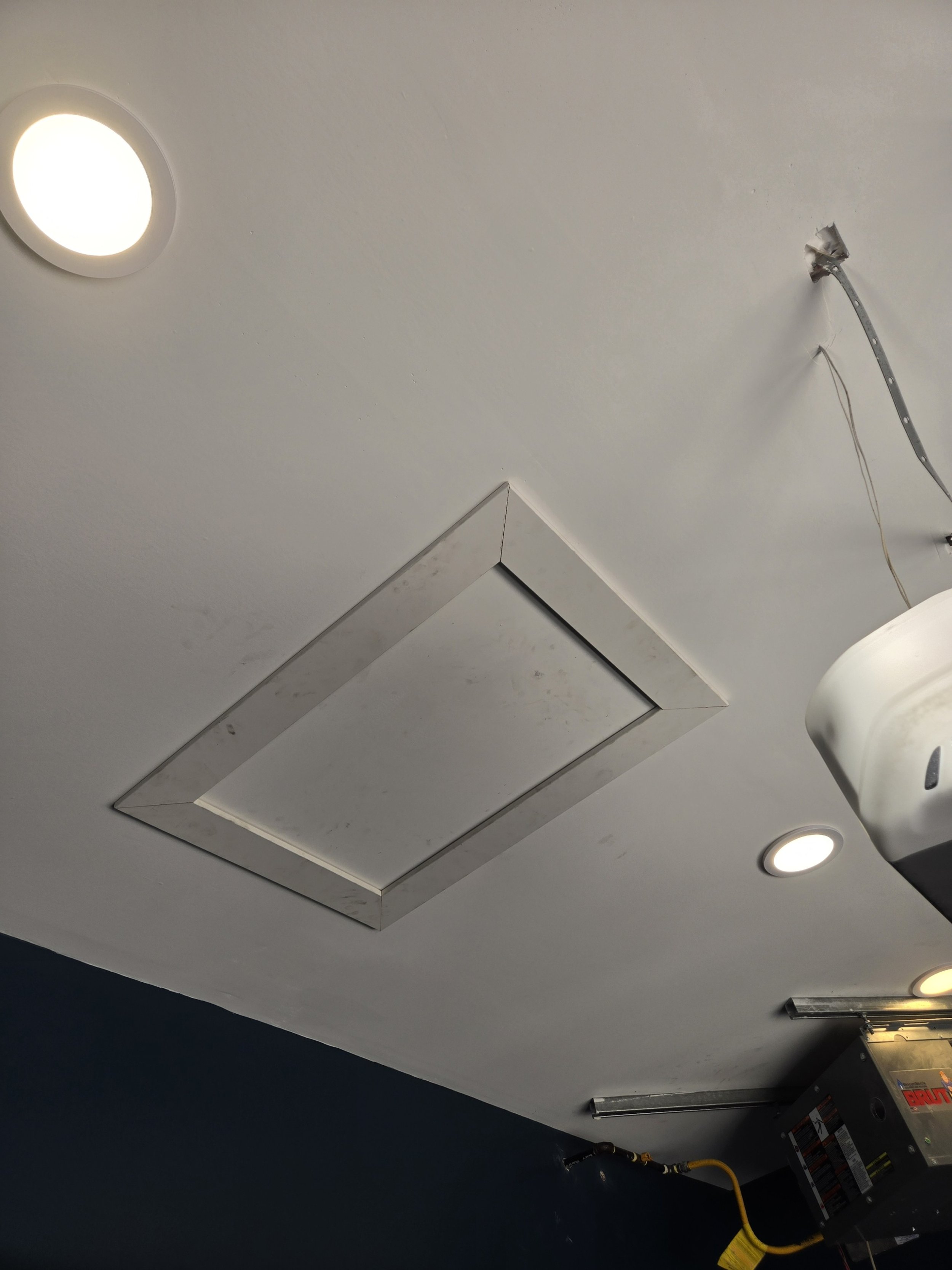 Ceiling with recessed lighting and HVAC access panel, some wiring and a garage door opener.