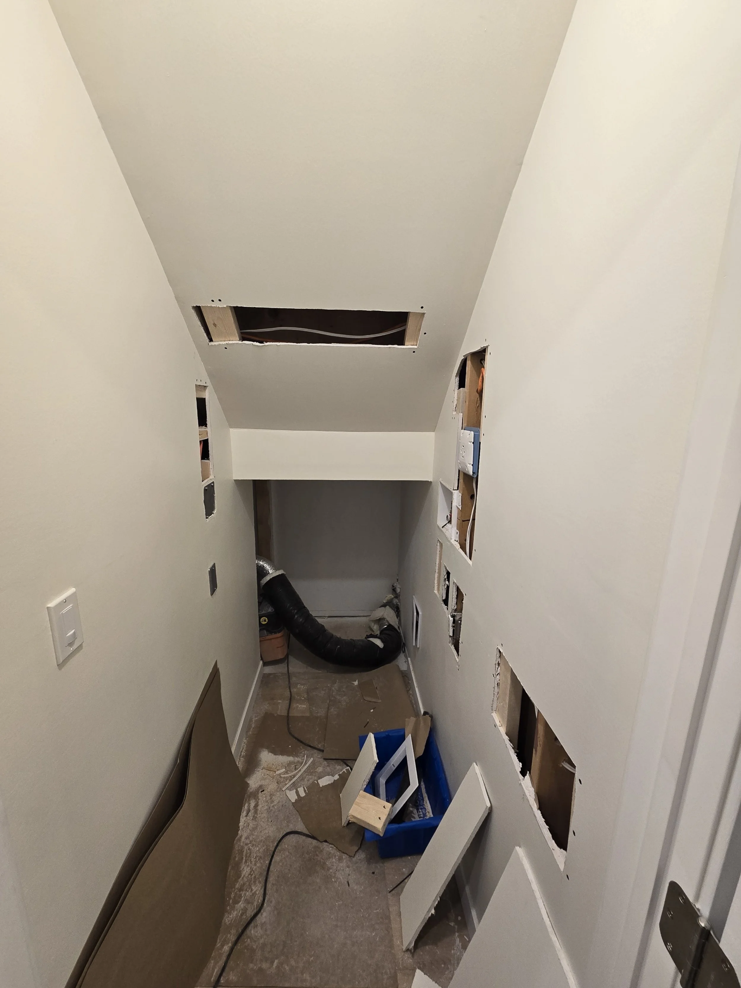 Construction space with drywall cutouts and pipes, tools, and cabinetry in progress.