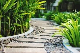 A stone pathway winding through a lush garden with green plants and trees.