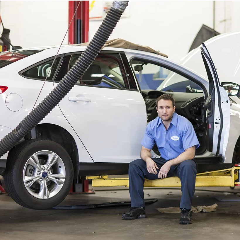 Smiling caucasian male mechanic sitting on lift