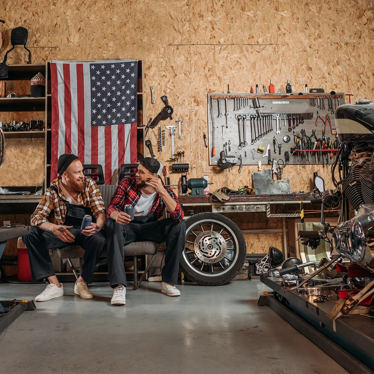 Two mechanics in plaid shirts having lunch in shop