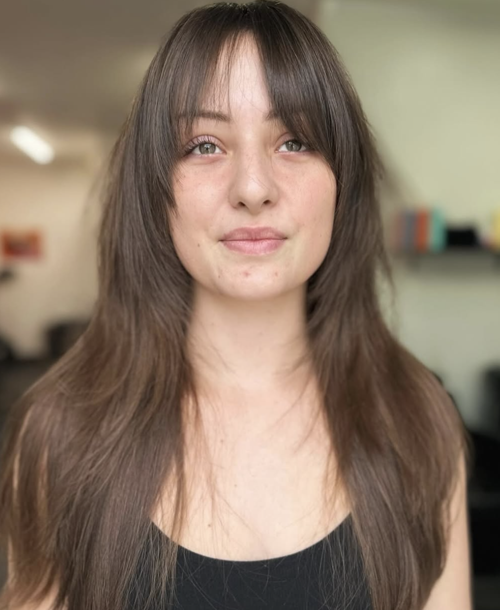 Woman with dark hair cut into layers with bangs