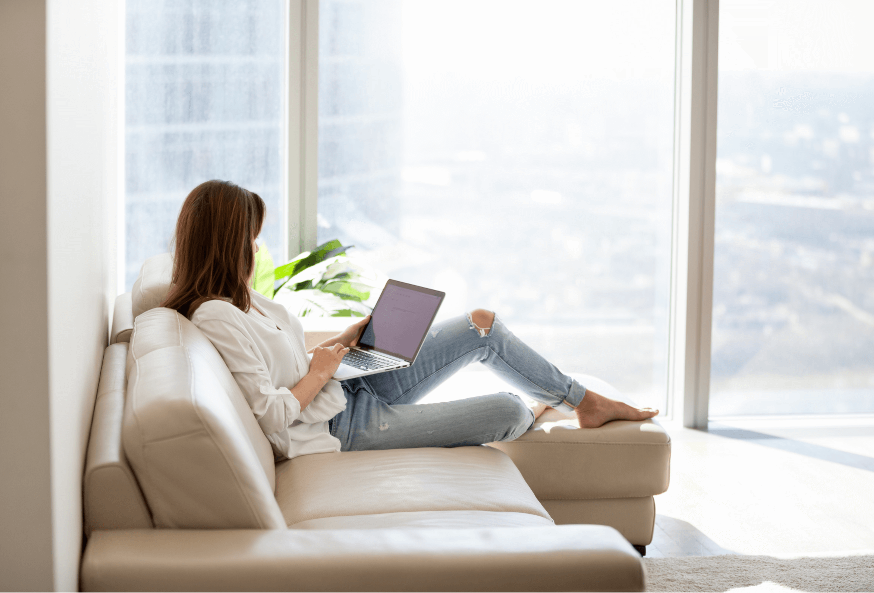 Woman sitting calmly at home, reading her Insights & Integration session summary on a laptop — reflecting in her own time.