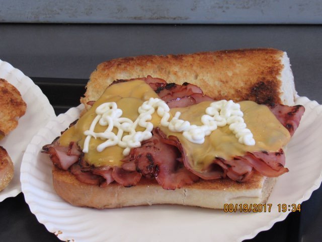Hot roast beef sandwich with mustard on a toasted bun, served on a paper plate