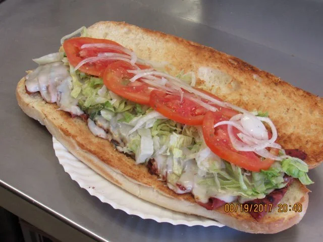Sub sandwich with lettuce, tomato slices, onions, and possibly mayonnaise inside a toasted hoagie bun.