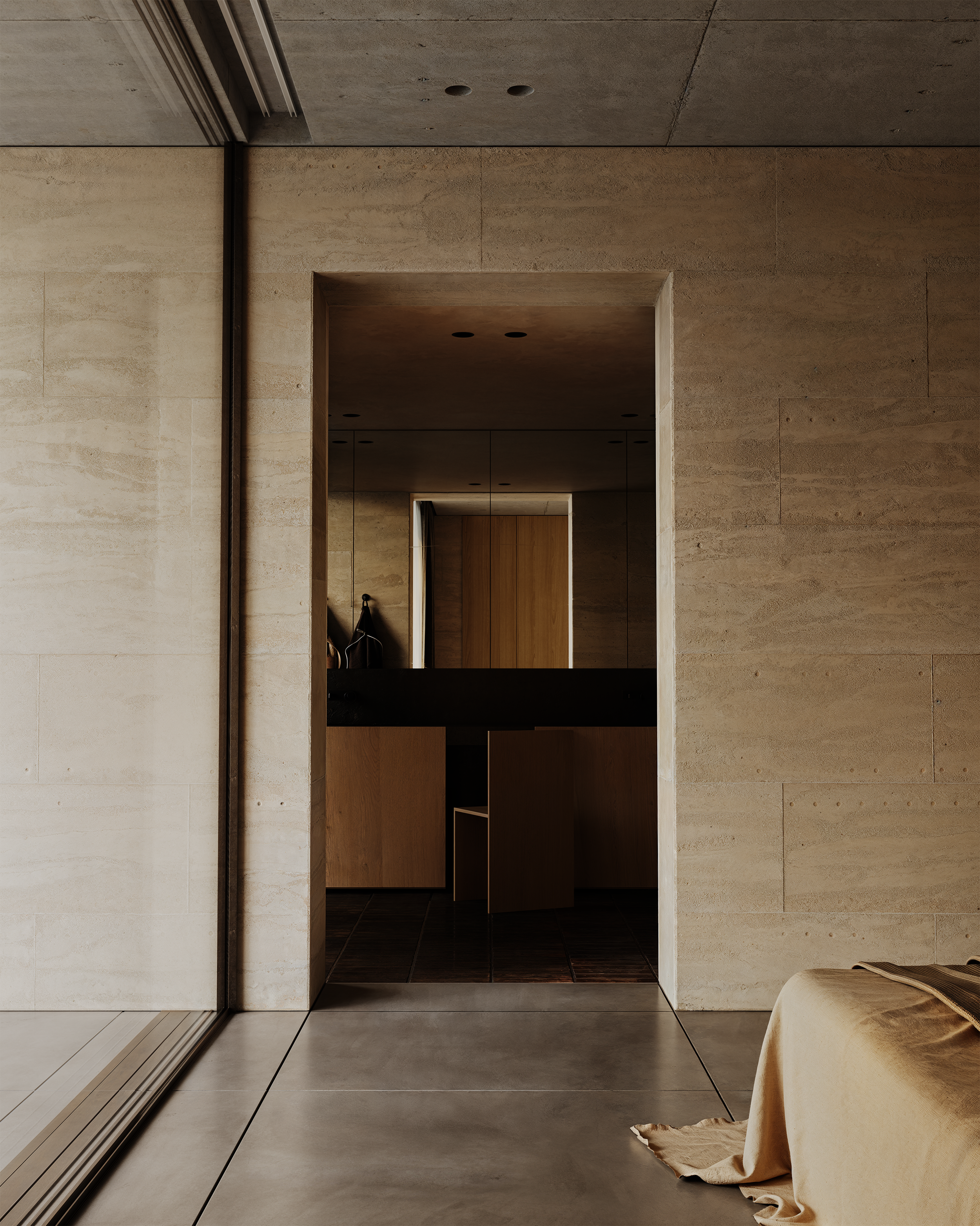 A minimalist interior with large light-colored tiled walls and floor, an open doorway leading to a small room with wood-paneled cabinets, and part of a bed with a beige blanket in the corner.