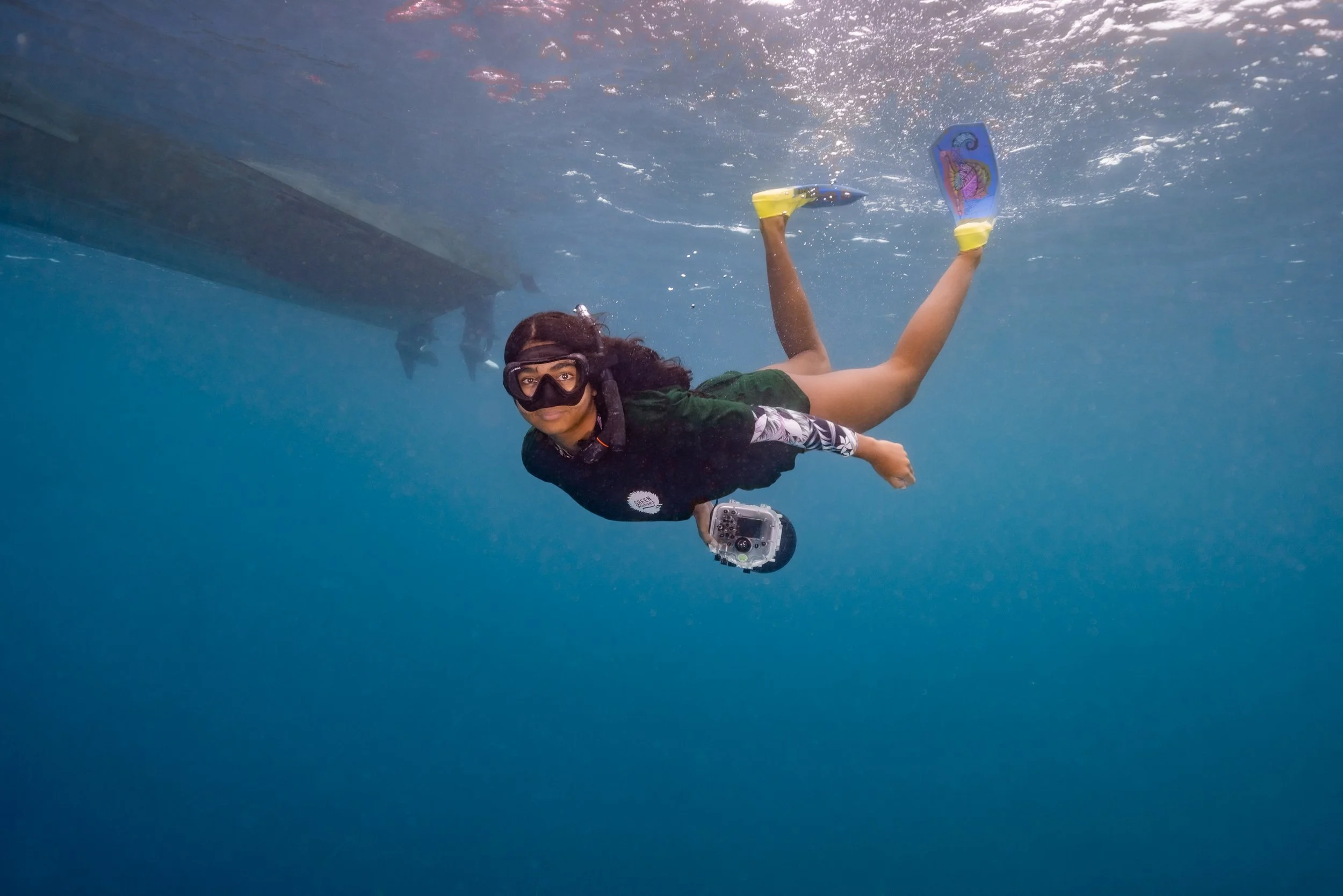 person snorkeling near a boat underwater while taking photos
