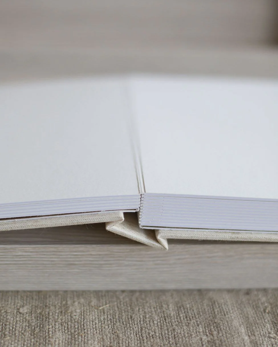 Close-up of an open blank white notebook resting on a textured light-colored surface.