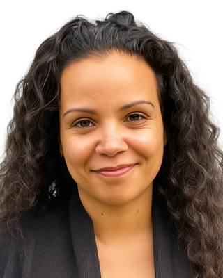 Close-up of a woman with curly brown hair, smiling at the camera against a plain background.