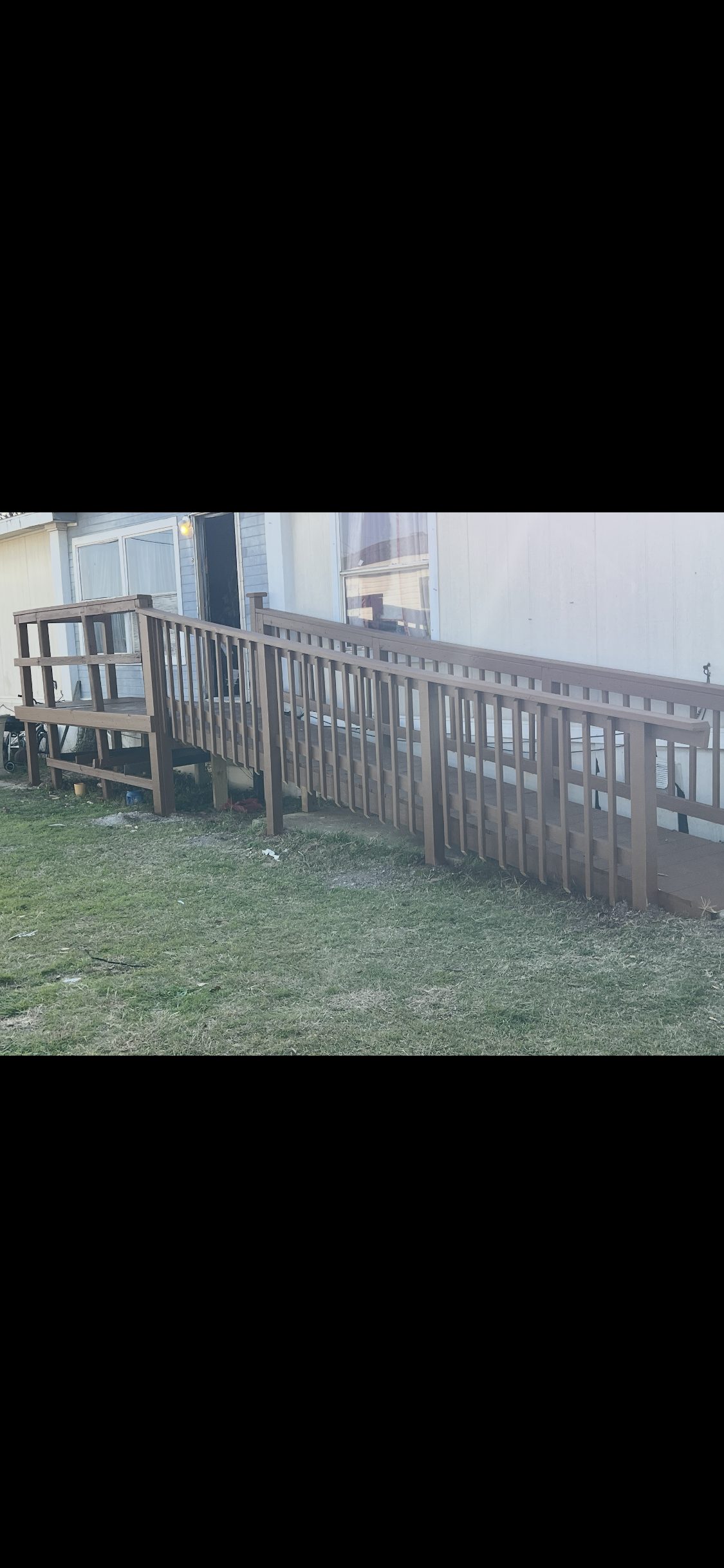 A wooden ramp with handrails leading to the entrance of a house.