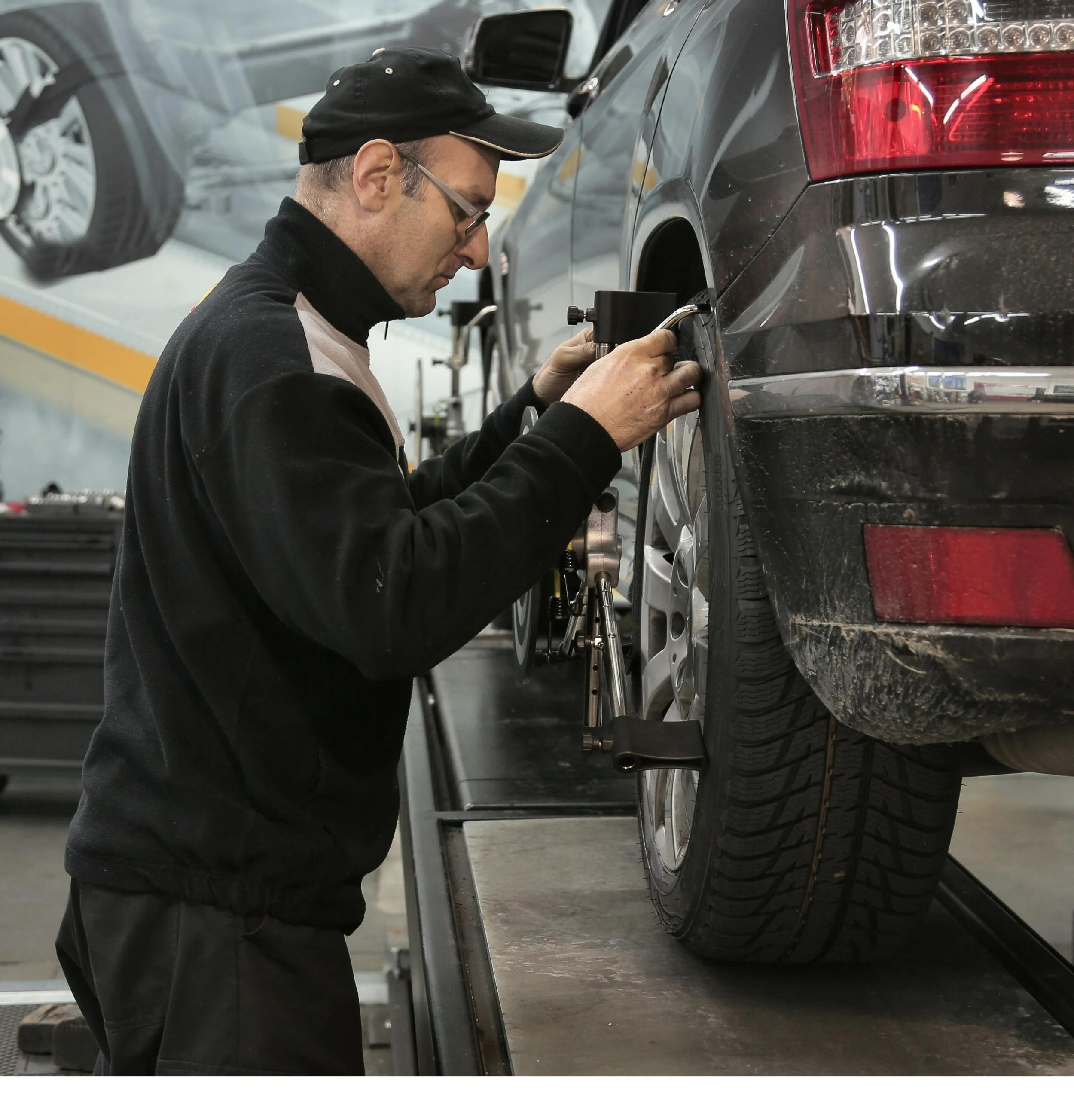 Automobile technician performing an alignment on a car in a garage.