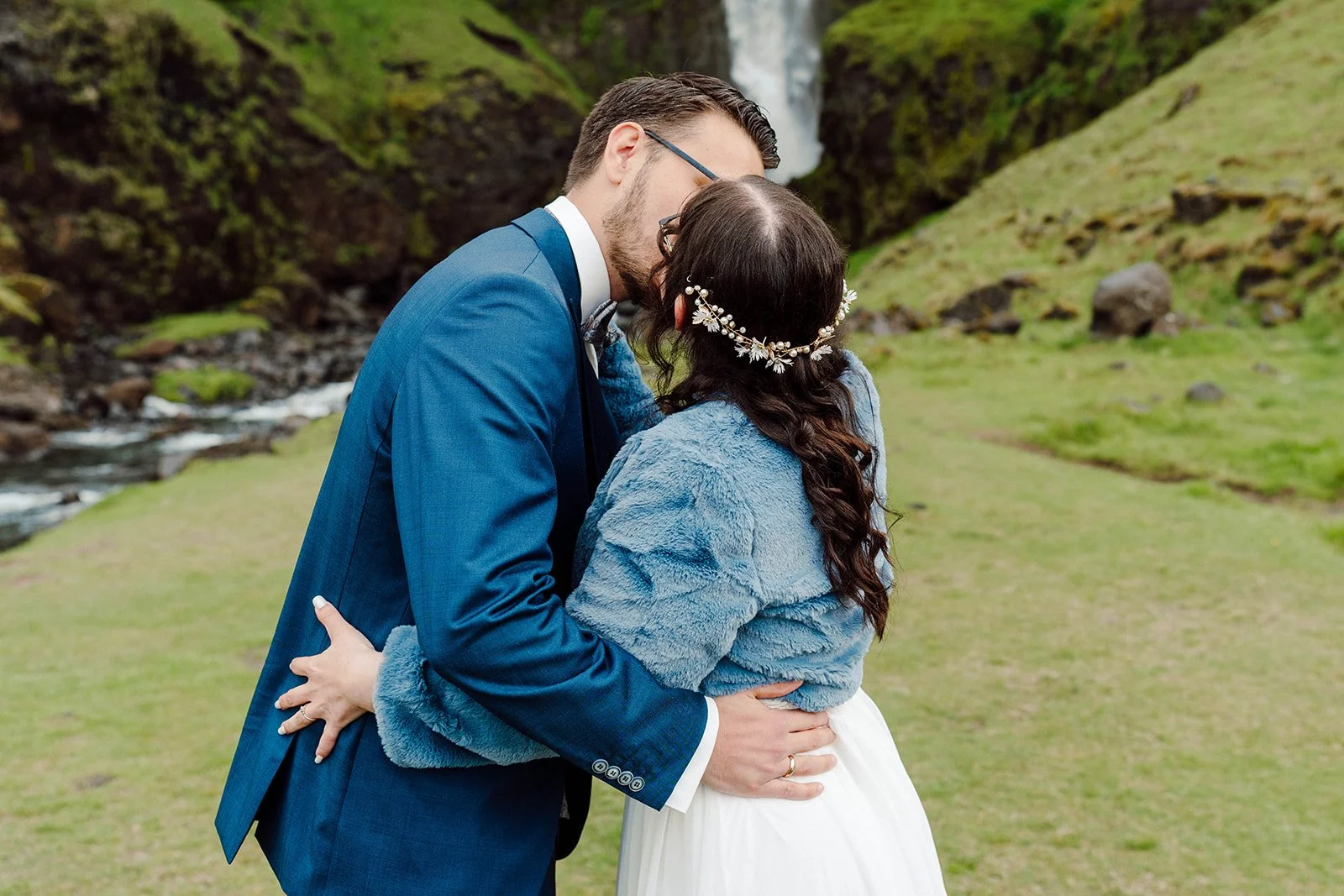 Bride and groom sharing their first kiss during an intimate waterfall elopement ceremony in Iceland
