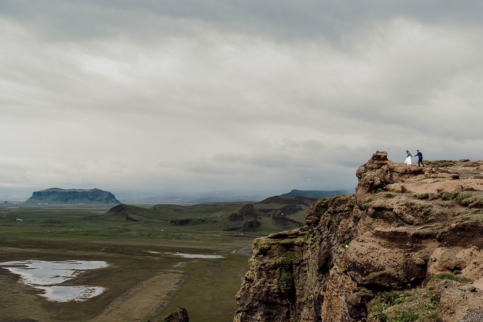 Epic elopement couple standing on cliff in Iceland highlands landscape