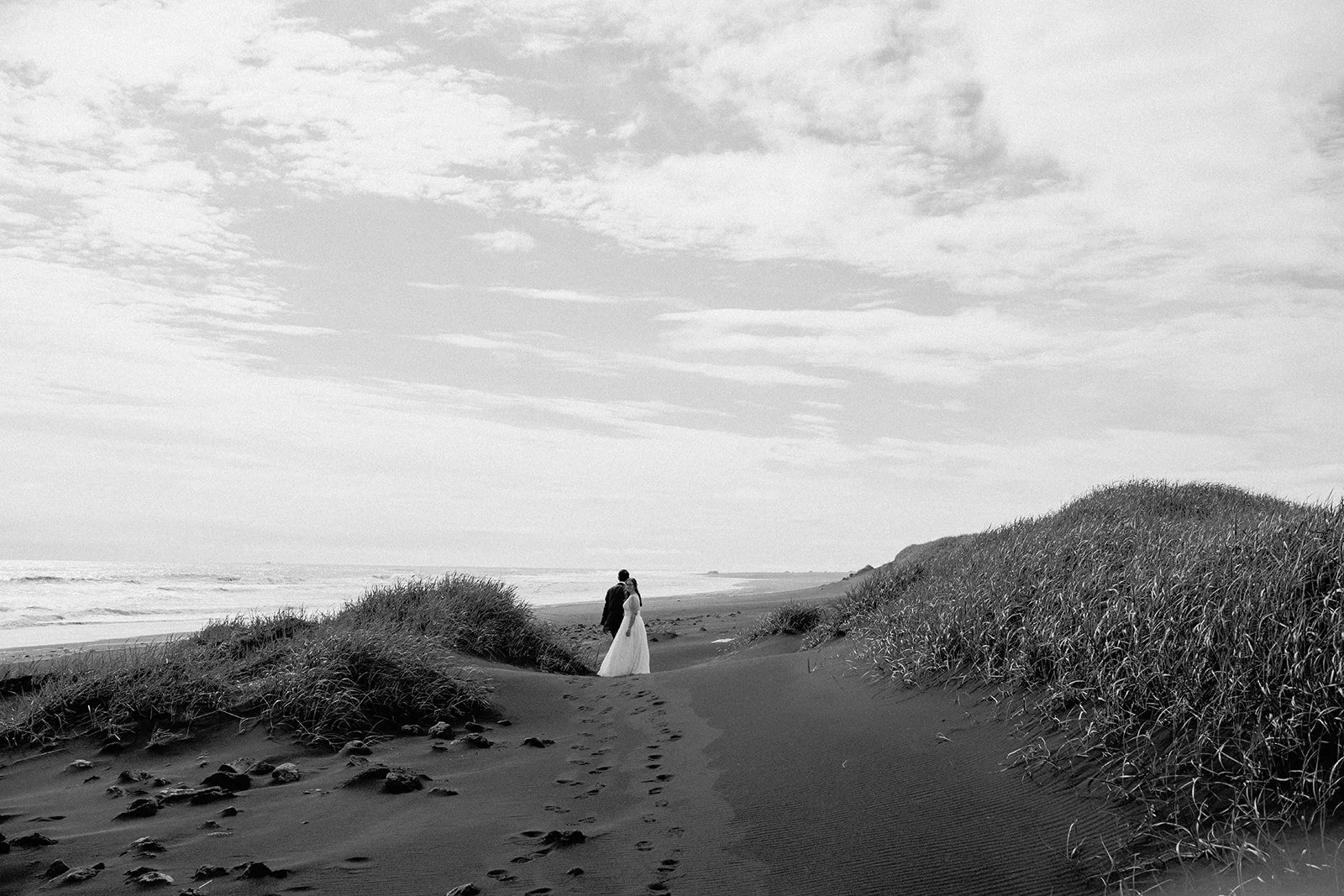 Black and white photo of elopement couple walking on black sand beach in Iceland