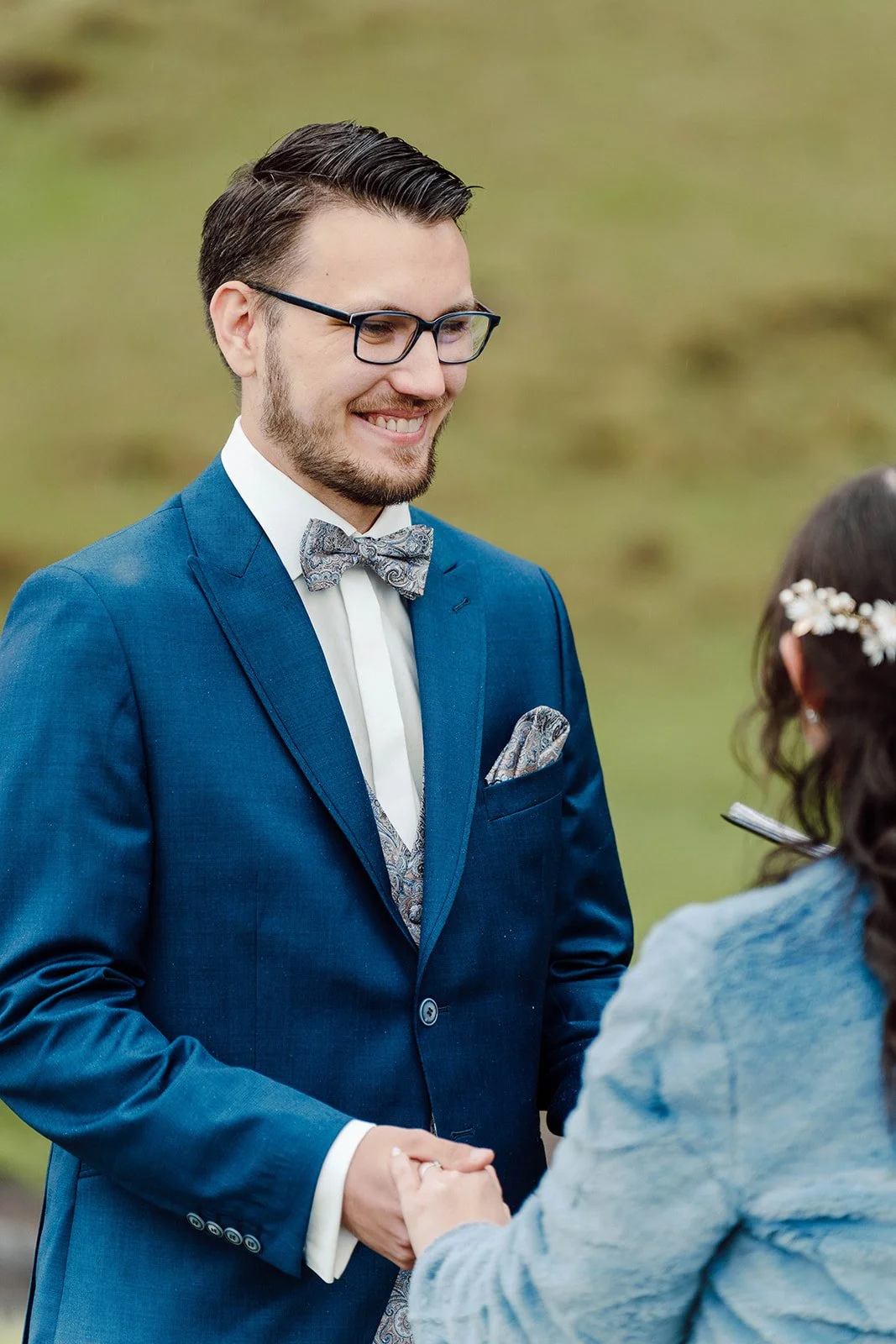 Smiling groom holding hands with his bride during their wedding vows at an Iceland elopement