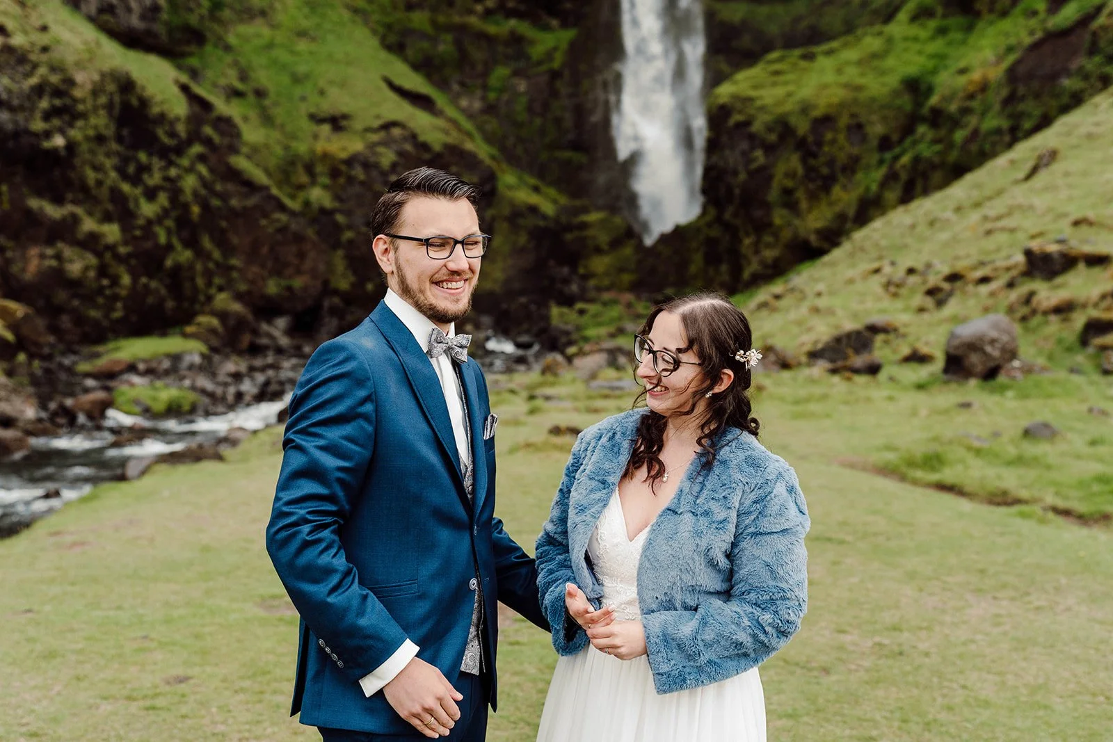 Happy newlyweds smiling together after their elopement ceremony near an Iceland waterfall
