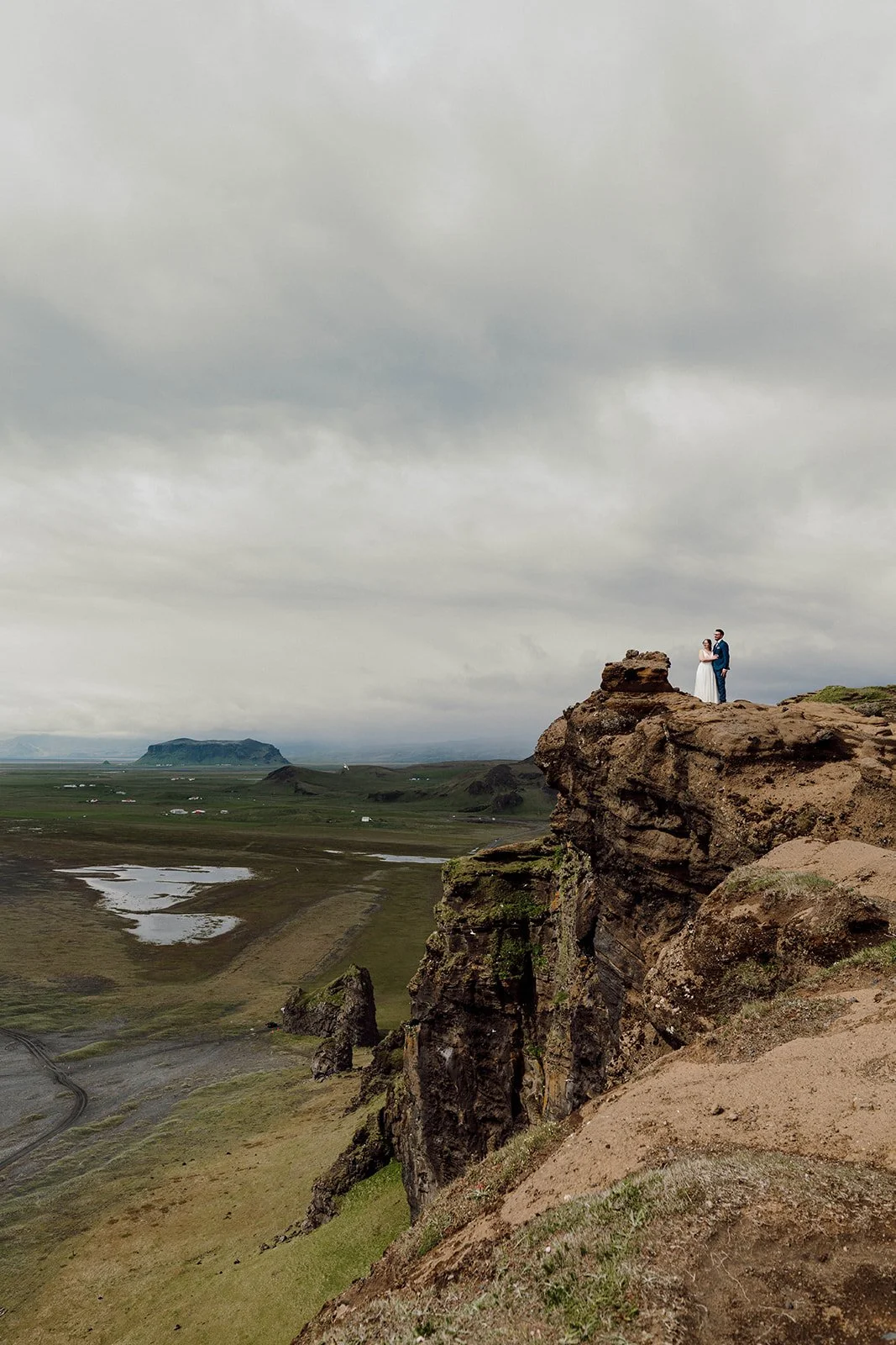 Elopement couple standing on dramatic cliff in Iceland highlands landscape