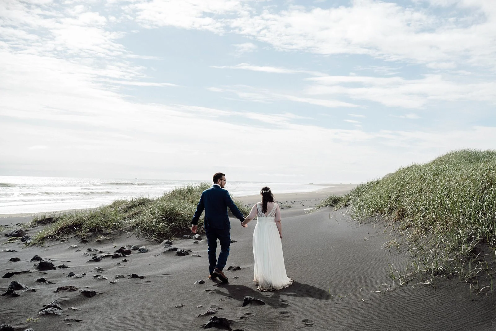 Elopement couple walking on black sand beach in Iceland