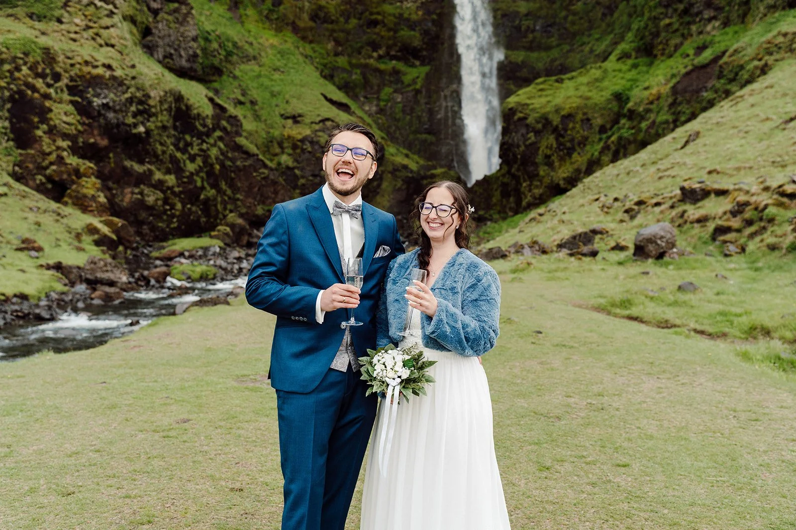 Newly married couple celebrating with champagne after their elopement near an Iceland waterfall