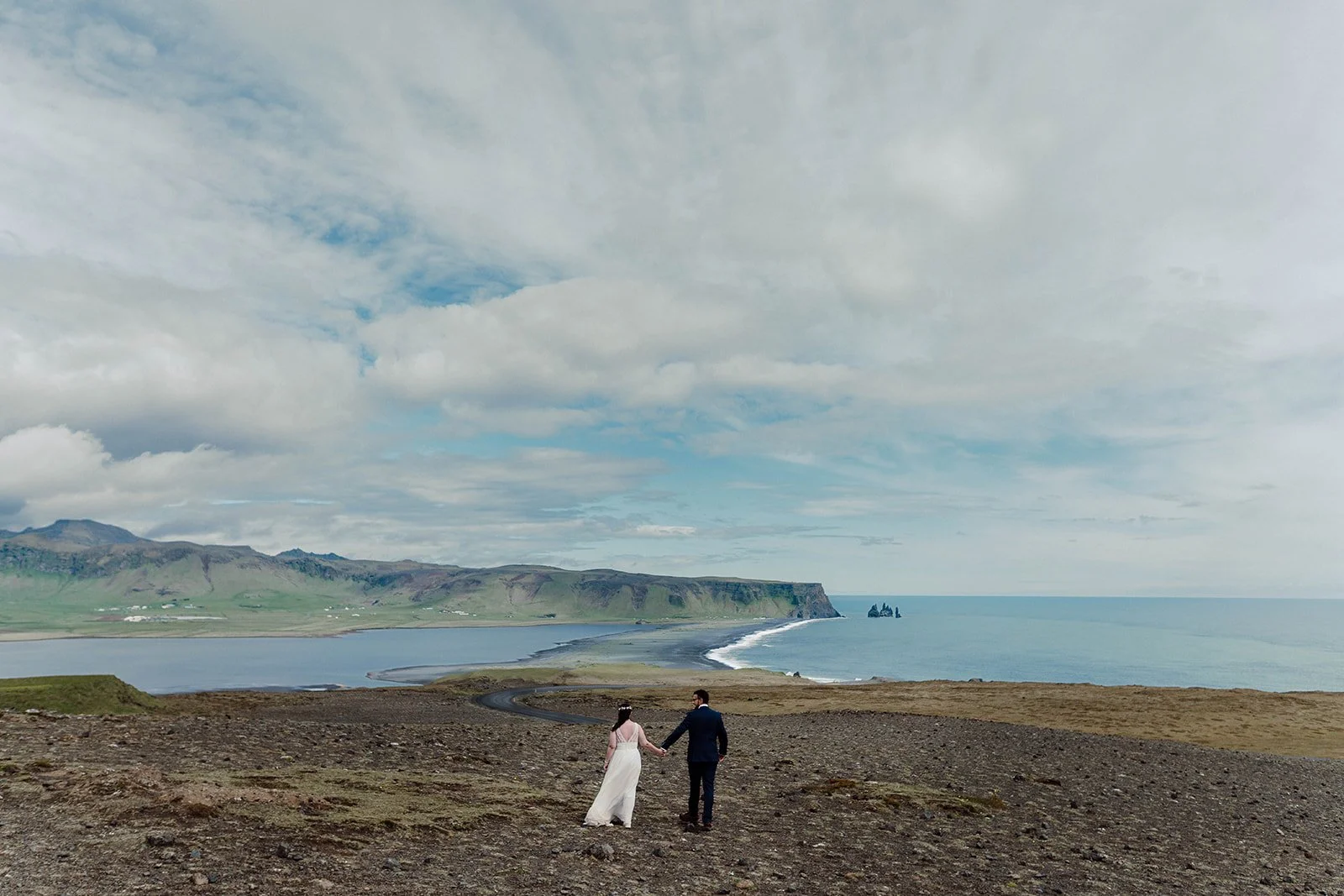Elopement couple walking toward ocean on Iceland south coast