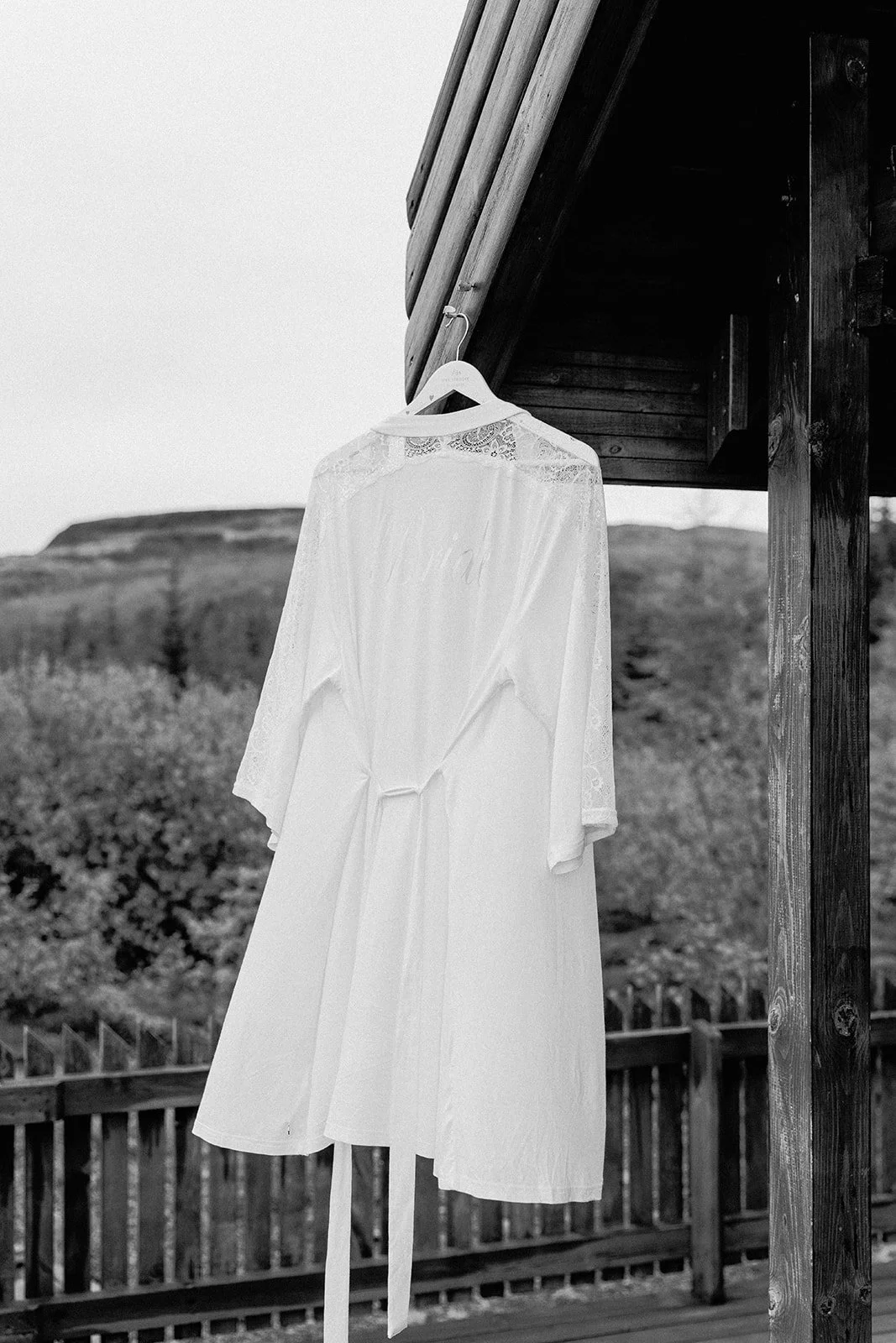 Black and white photo of a bridal robe hanging outside a cabin during an Iceland elopement getting ready