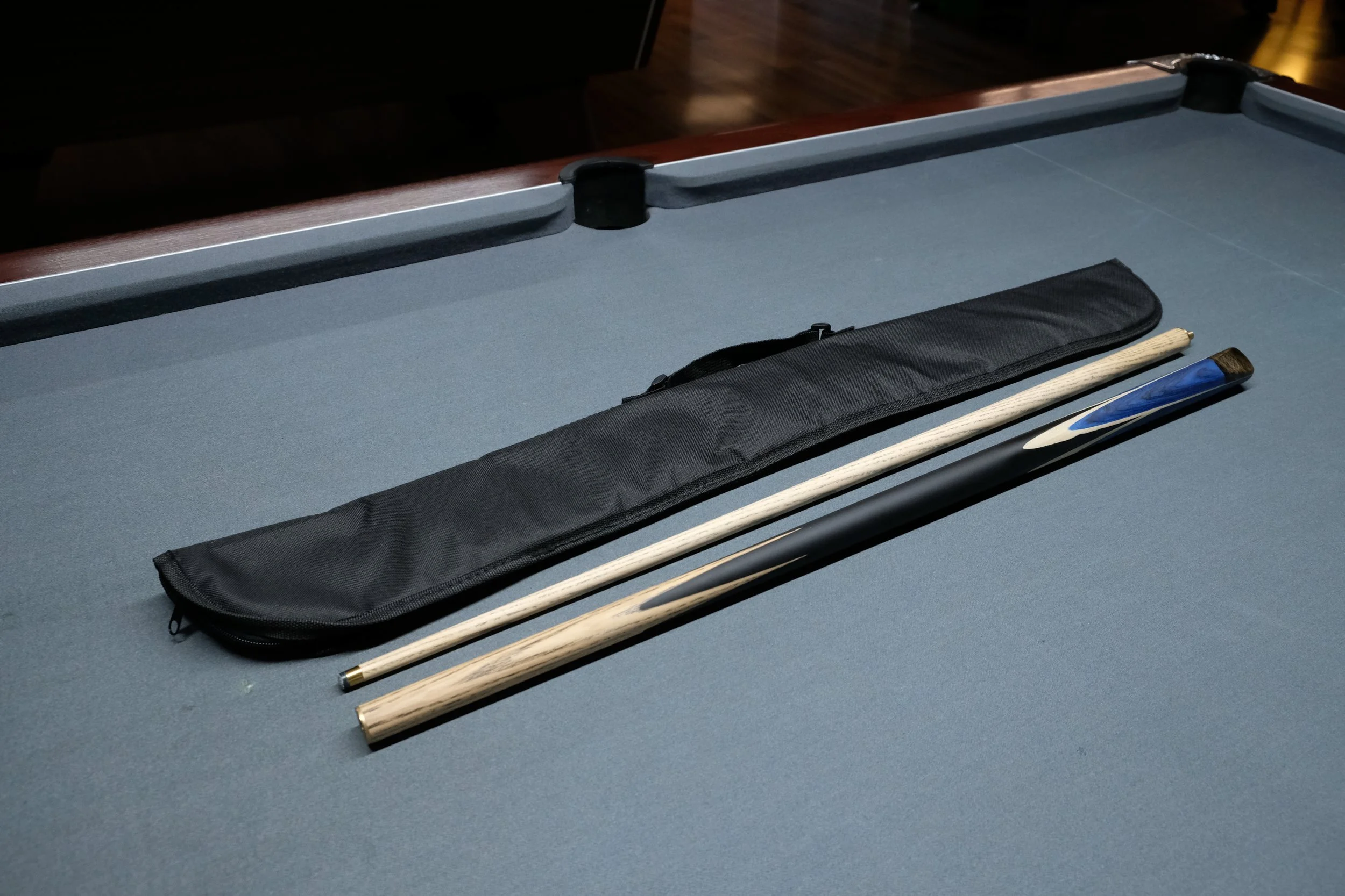 A pool cue stick with a black leather case on a pool table.