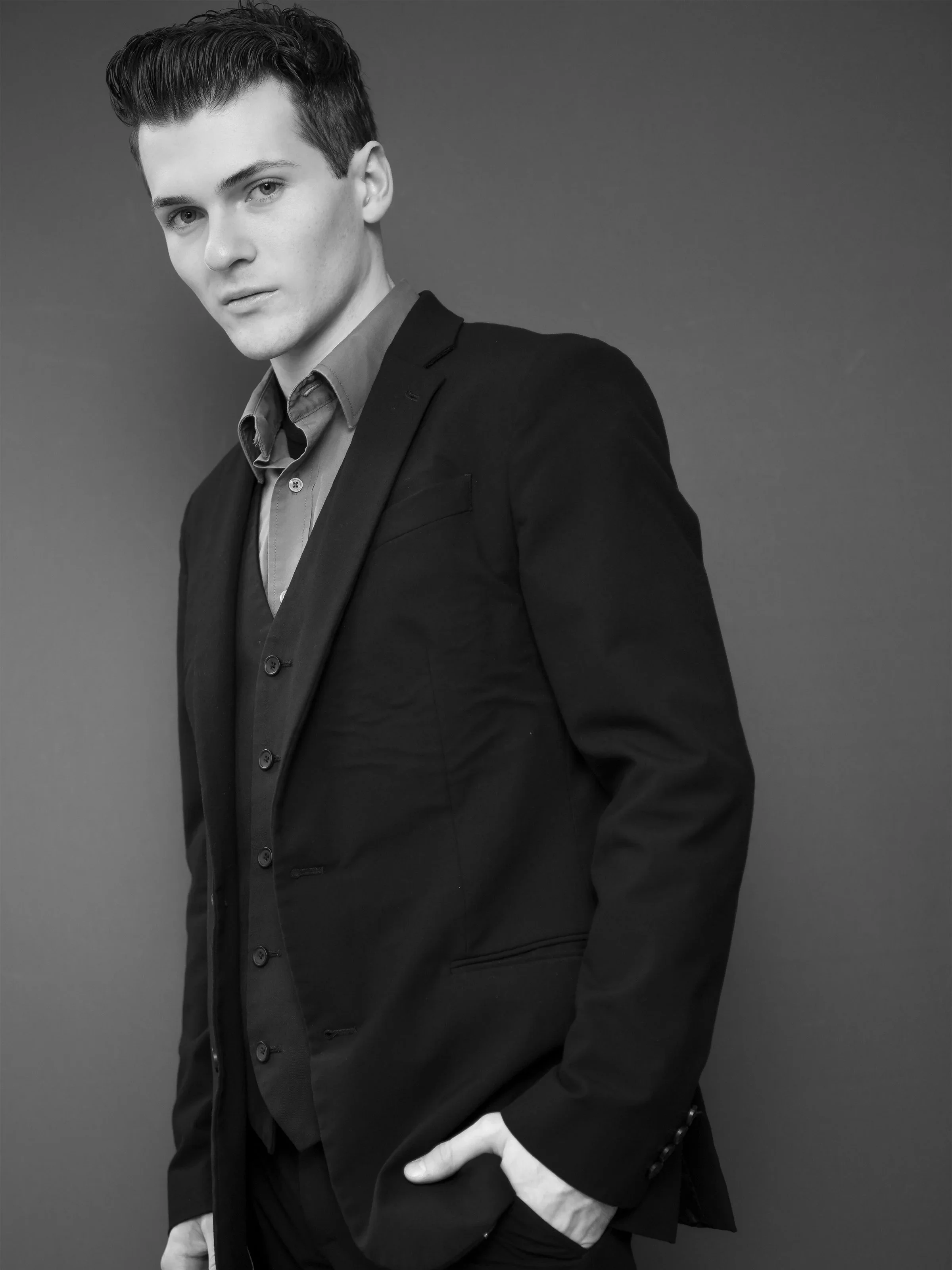 Benjamin Rocha with styled hair, dressed in a suit jacket over a button-down shirt, looking confidently at the camera against a plain background.