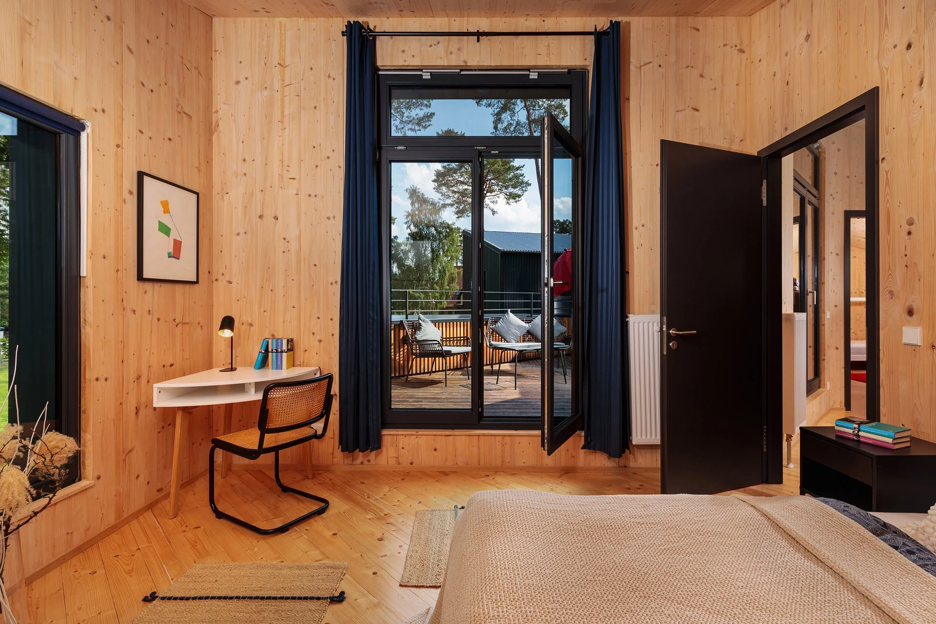 Schlafzimmer mit Holzverkleidungen, offener Balkon mit Sitzgelegenheiten, dunkle Türen und Fenster, helle Bettwäsche, moderner Stil.