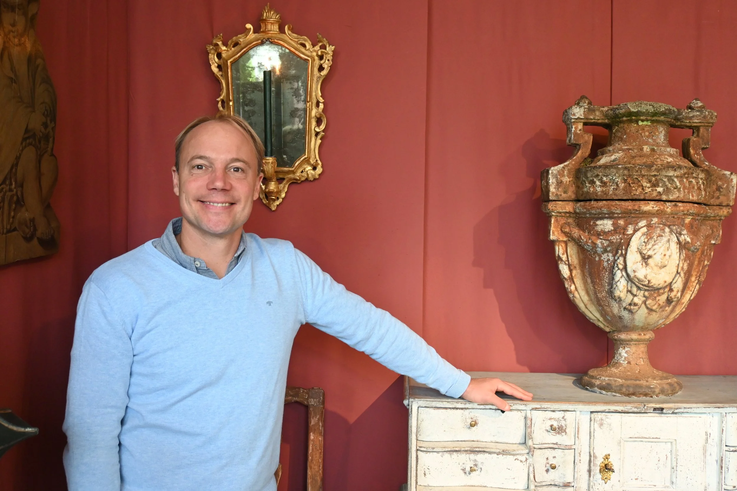 Un homme souriant devant un secretaire , une vasque et un petit miroir