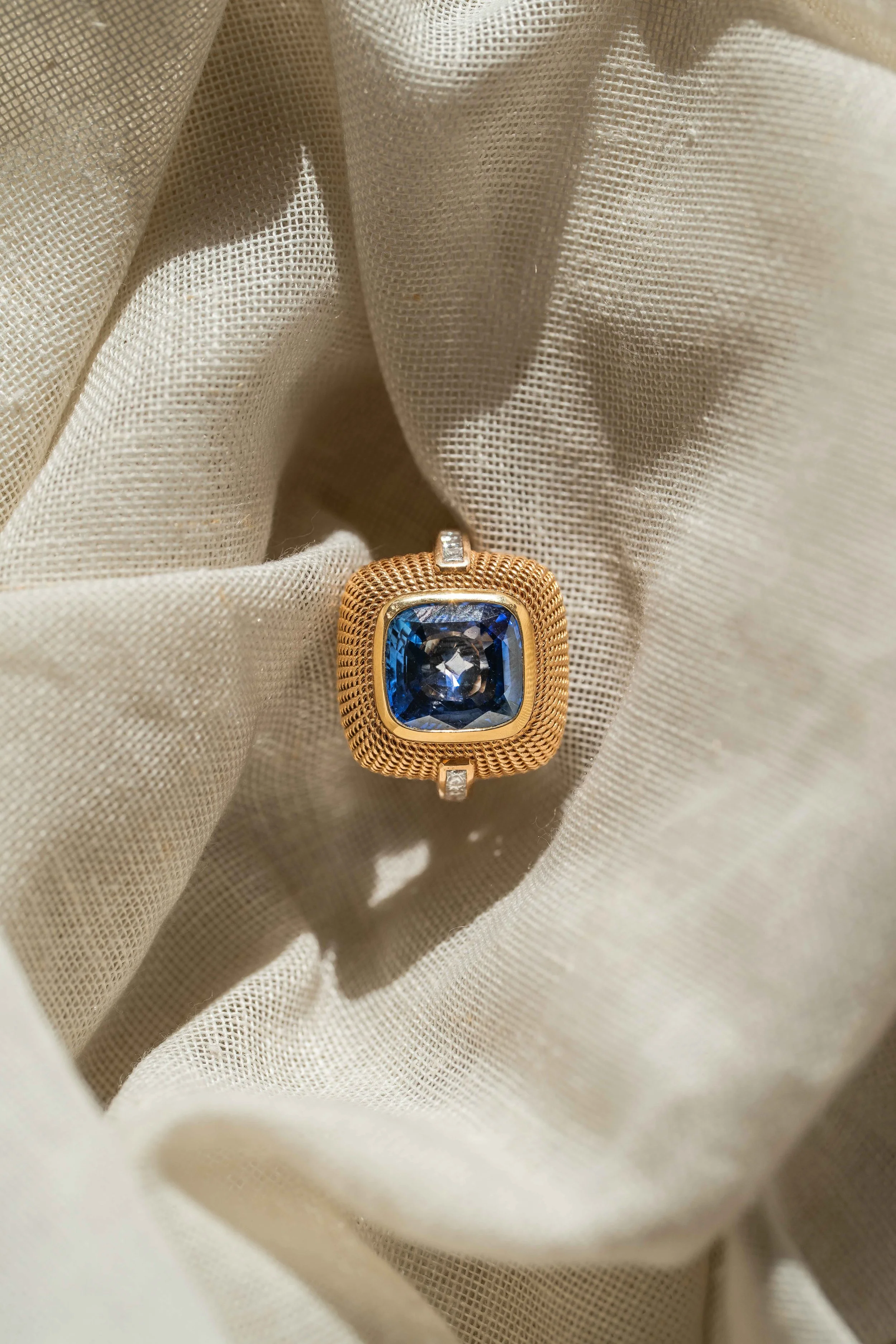 Louh Jewellery — bague dorée à pierre bleue sur un tissu clair