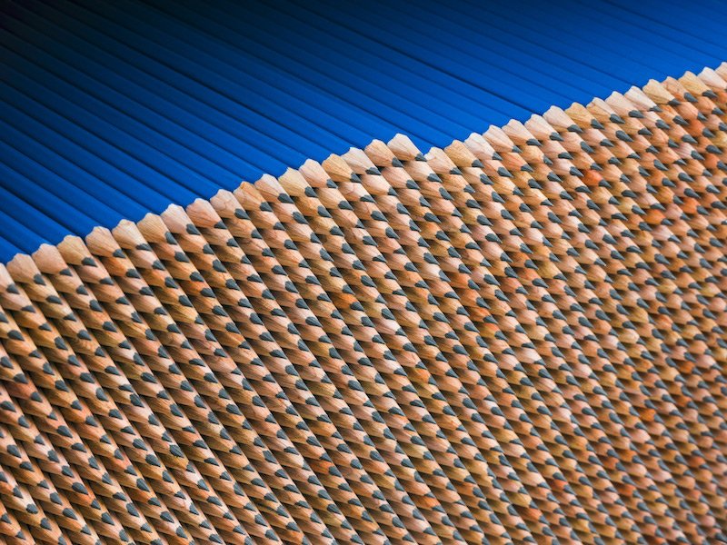 Close-up of scattered wooden pencils with black tips on a blue surface.