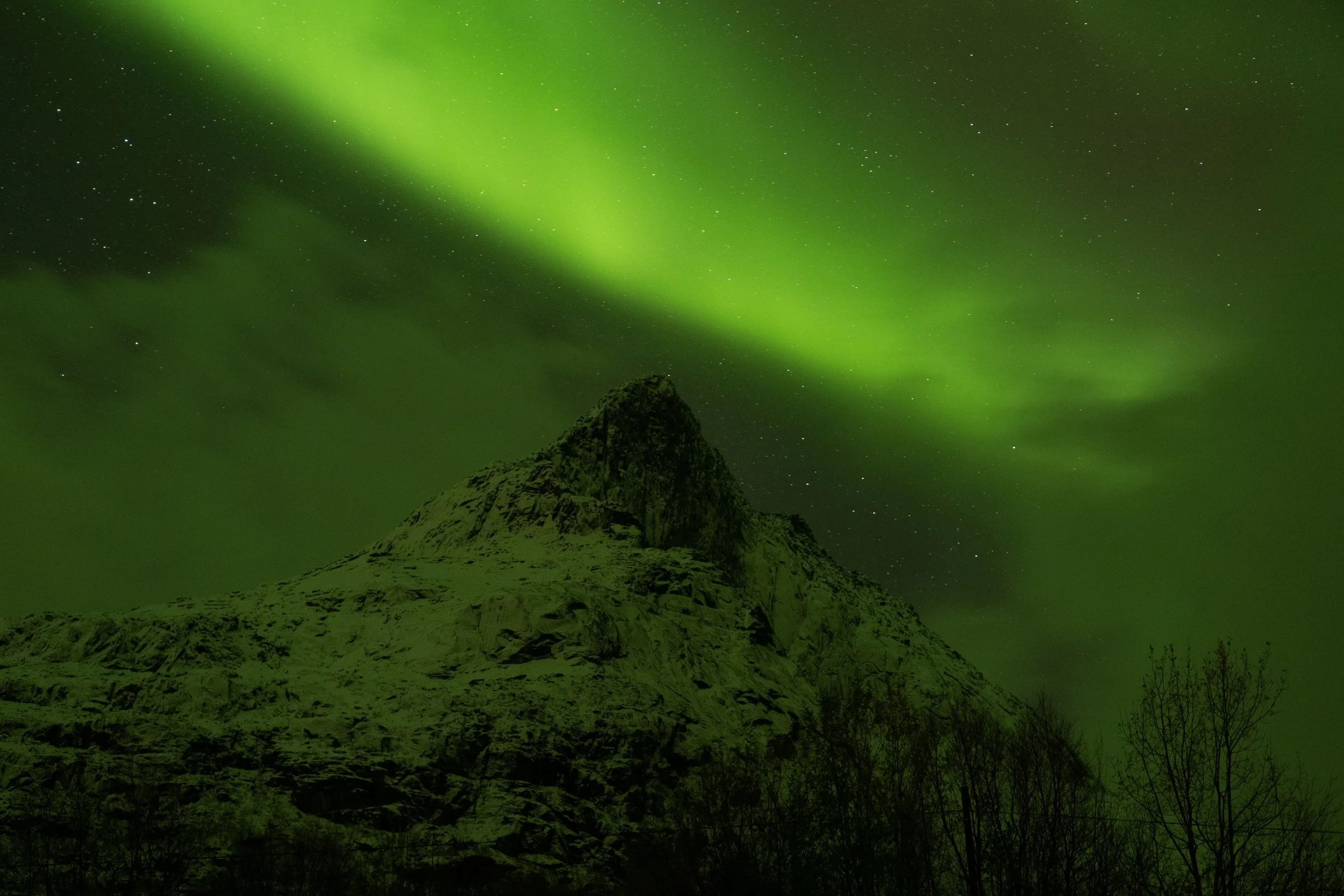 Northern lights over a snow-covered mountain at night.