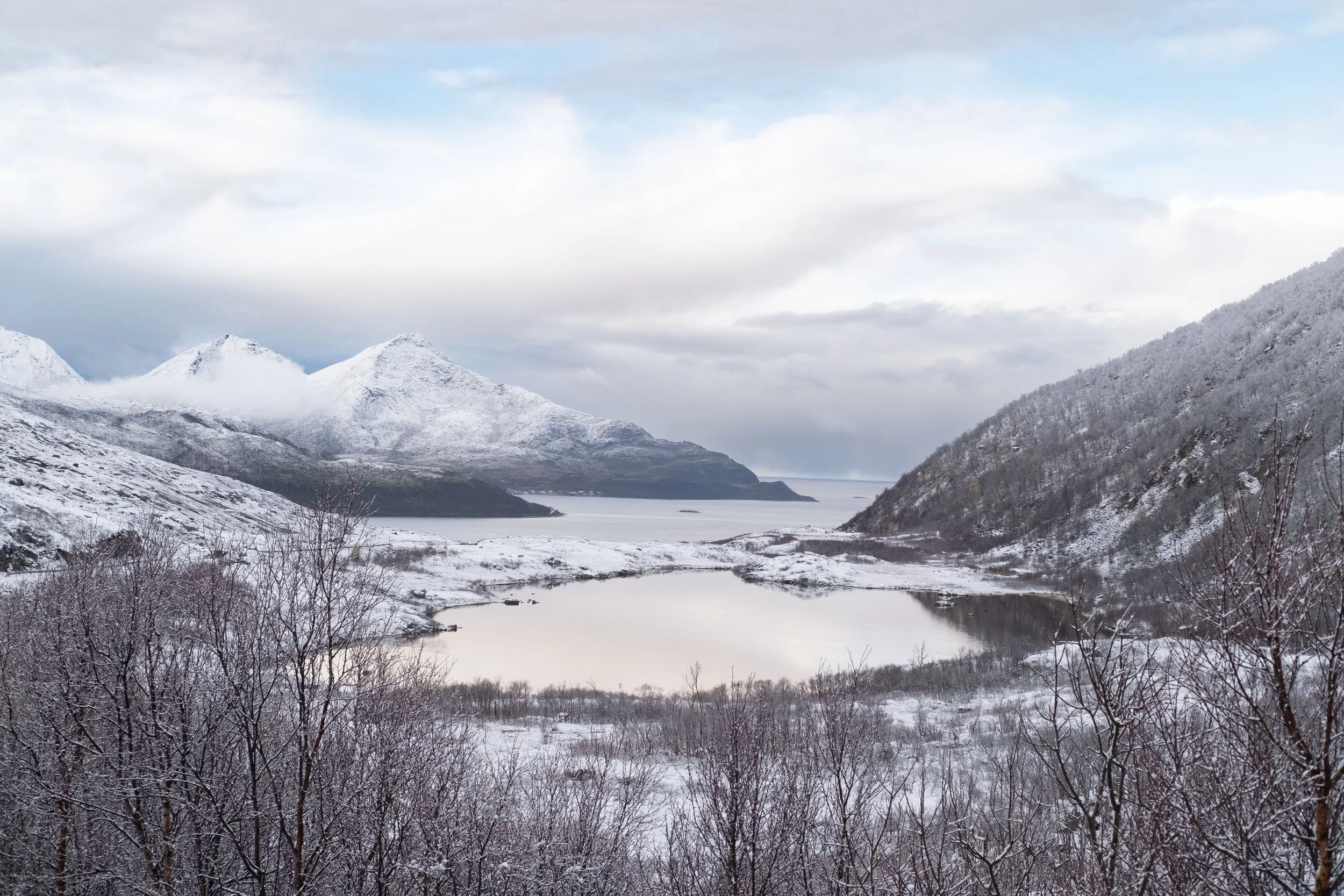 Snow-covered mountains surrounding a body of water in a winter landscape.
