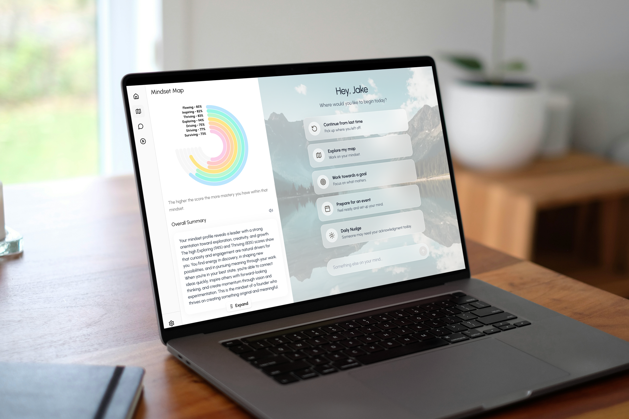 Laptop on a wooden desk displaying a mindfulness app's map and options, with a blurred background of a living space and natural light.