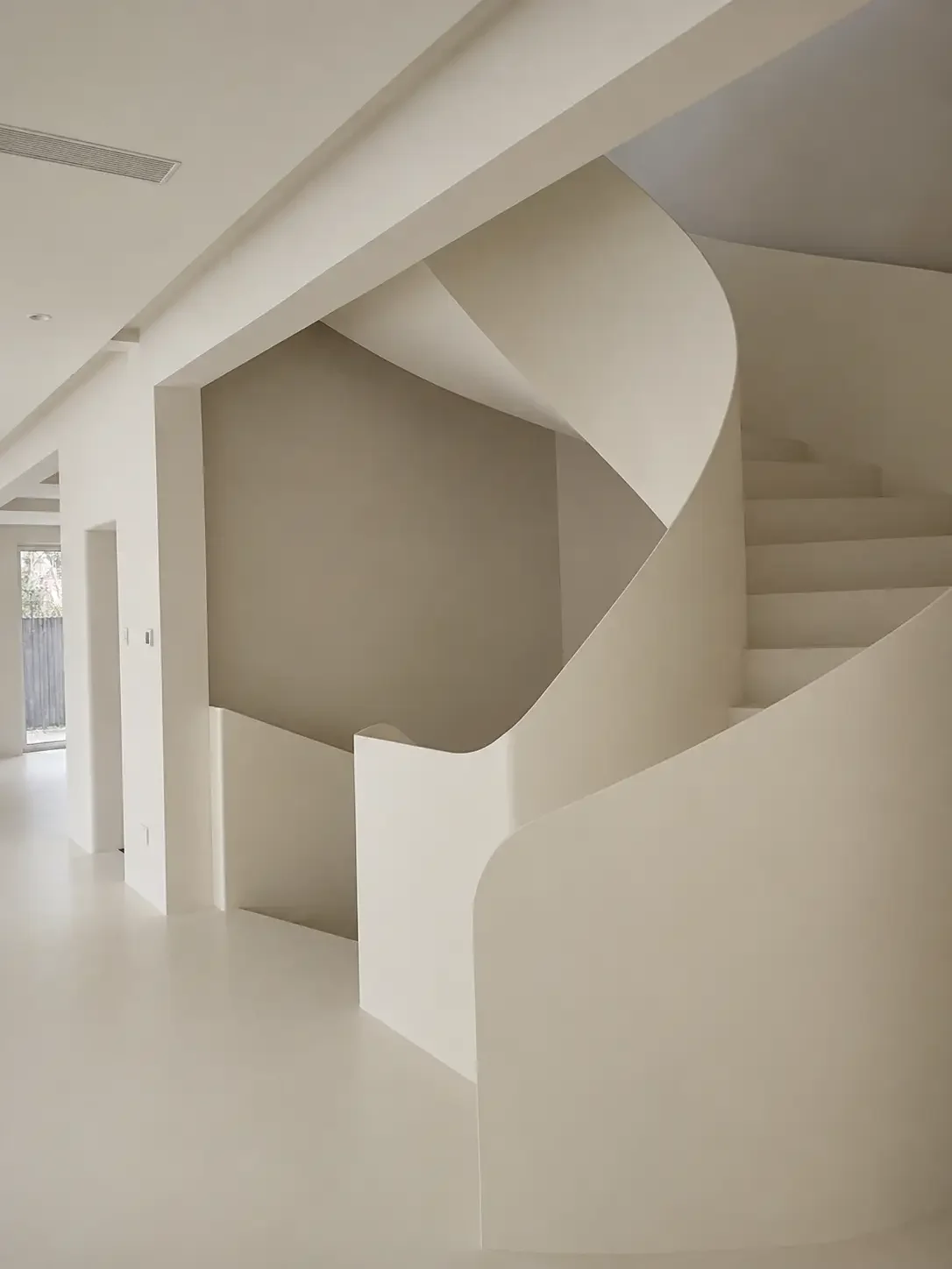 Curved staircase finished with light microcement in a modern villa interior in China.
