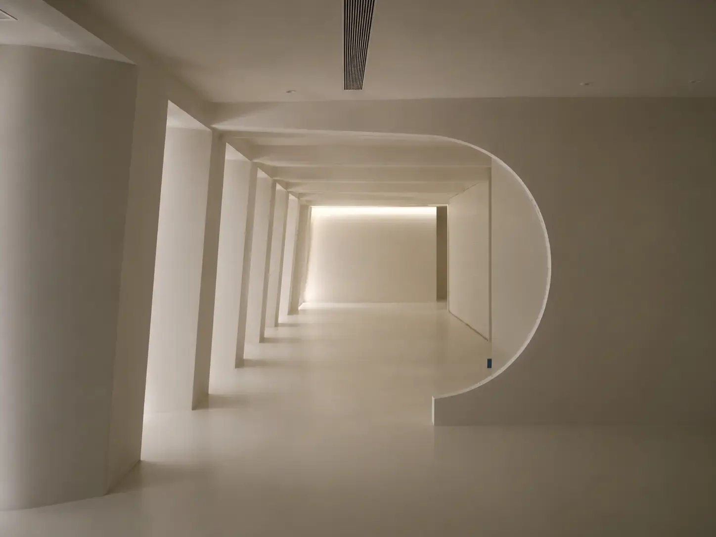 Curved opening and seamless microcement surfaces in a modern villa interior in China.