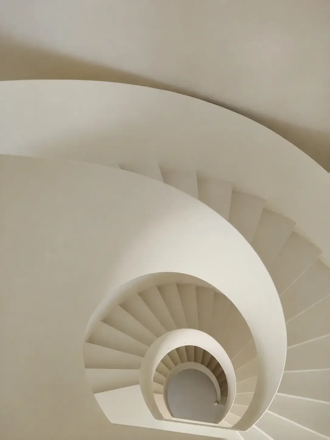 Curved microcement staircase in a China villa interior with seamless light beige surfaces.
