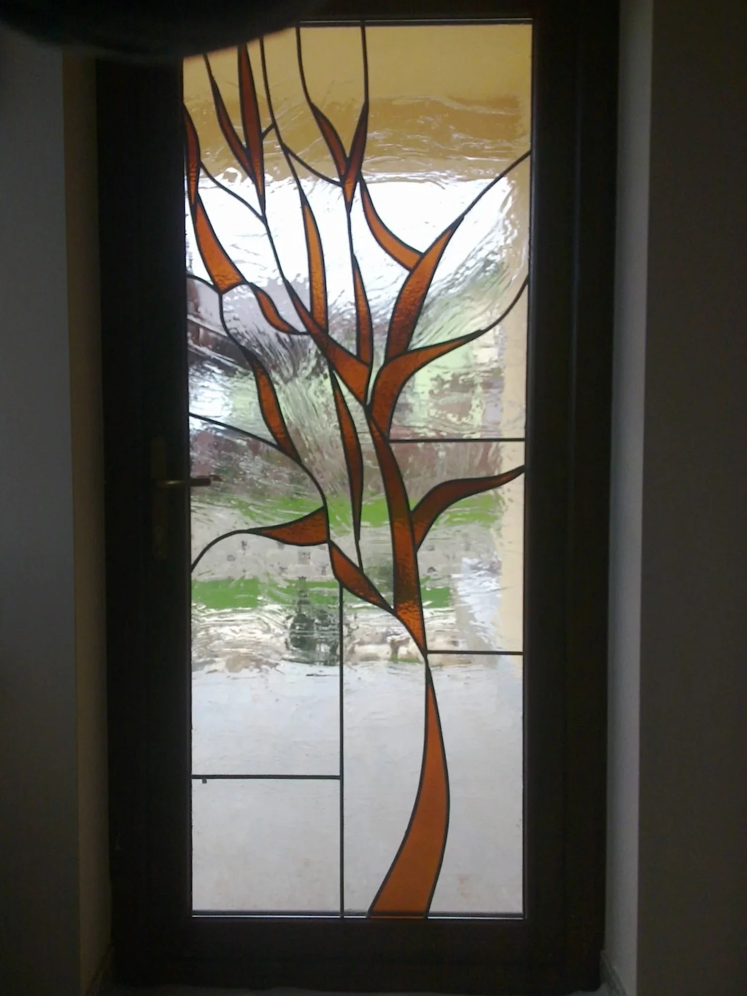 Decorative glass door featuring an abstract tree design with orange and brown branches.