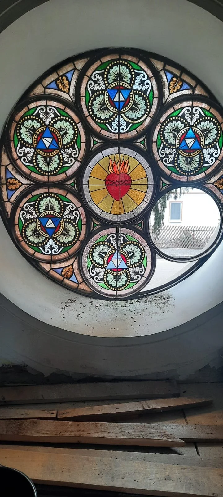 Colorful stained glass window featuring a central flaming heart and geometric patterns.