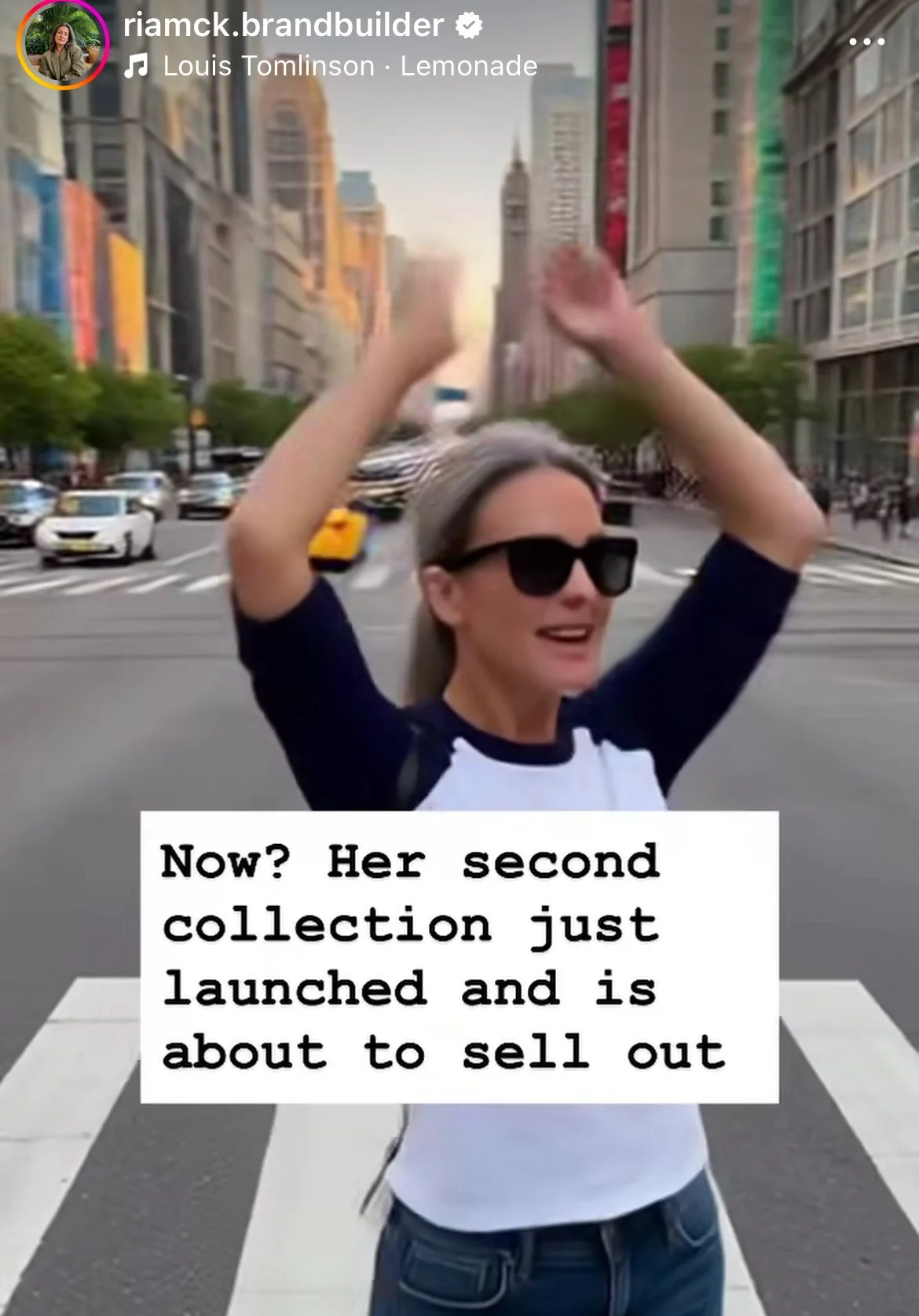 A woman wearing sunglasses and a black and white shirt smiling while standing in a city crosswalk, with tall buildings and traffic in the background, and a caption that reads 'Now? Her second collection just launched and is about to sell out'.