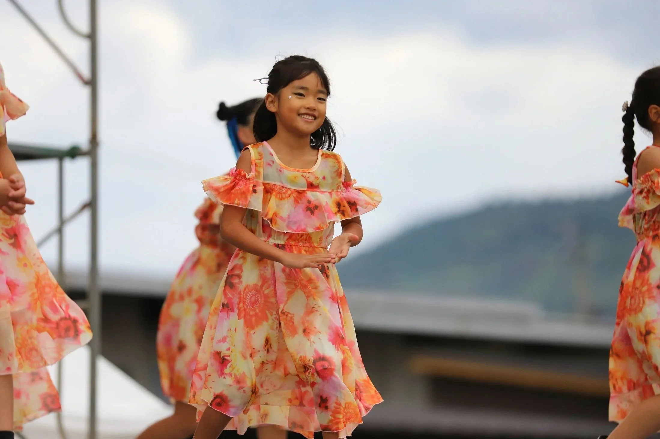 花柄の衣装を着た少女たちが屋外でダンスをしている