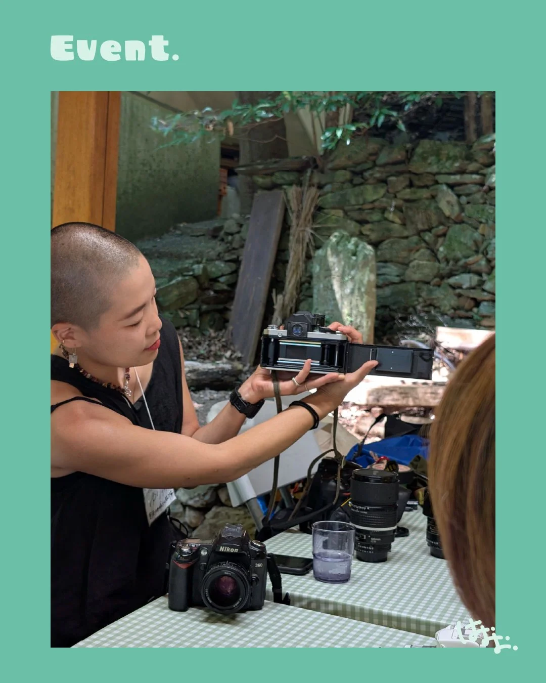 カメラを持ち女性が写真を撮影している様子。屋外の岩や木々の背景。