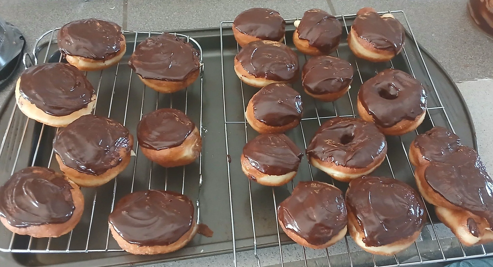 Chocolate-glazed donuts cooling on a wire rack.