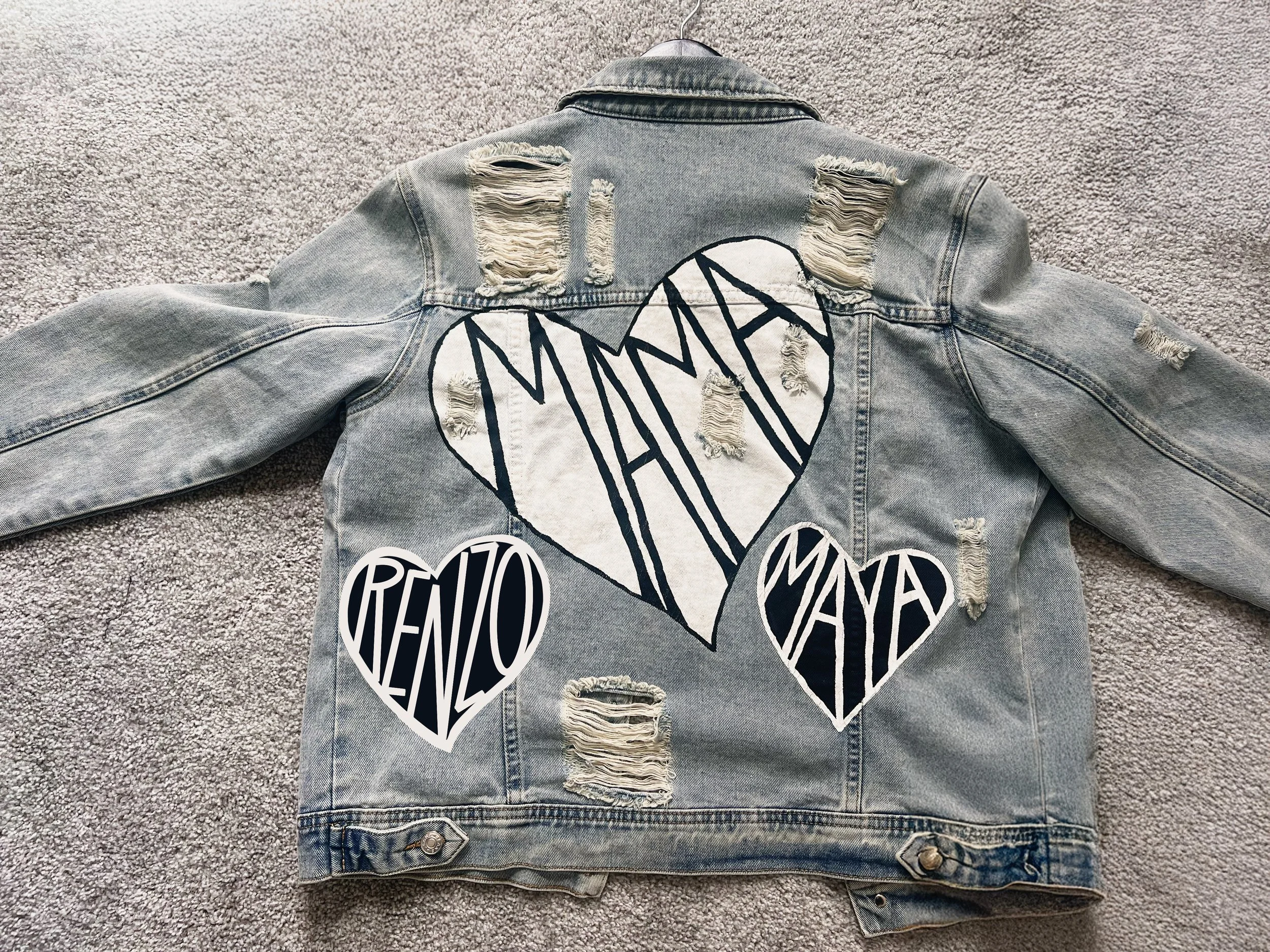 Distressed denim jacket with large hearts and the words 'MAMA,' 'MANA,' and 'RENTRO' painted on the back.