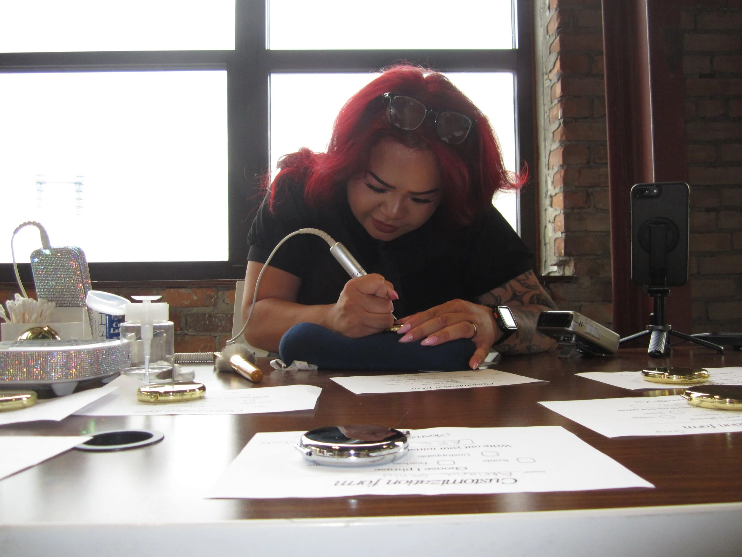 Live event calligraphy engraver customizing compact mirrors as guest favors for corporate event.