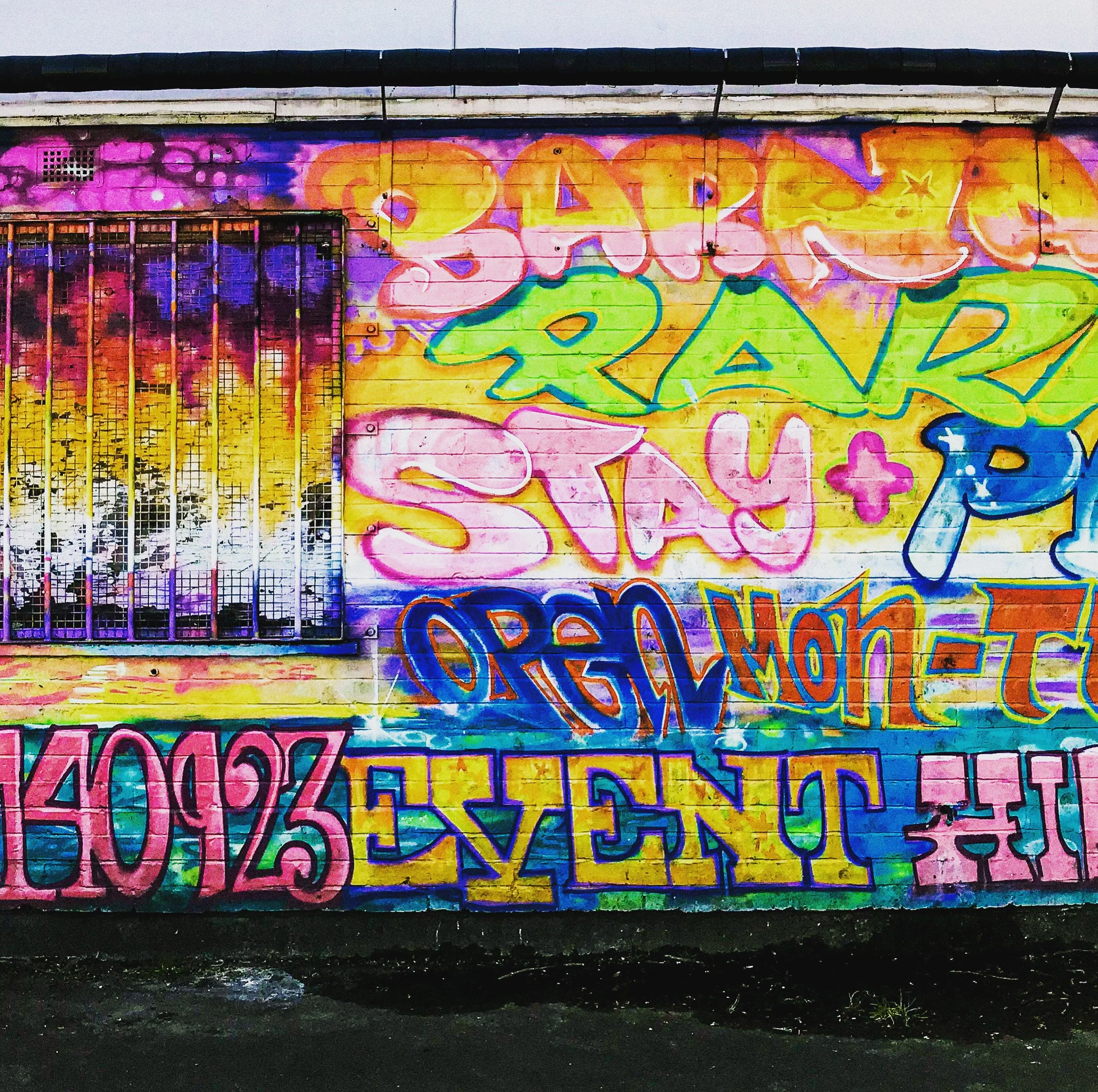Colorful graffiti art on a wall with words like 'Dance,' 'Share,' 'Stay,' 'Respect,' and 'Love' in vibrant, overlapping letters.