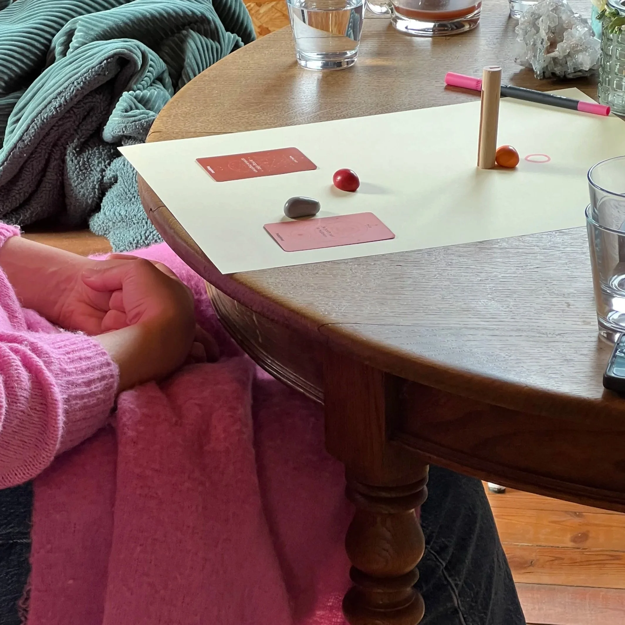 Gezelschap speelt een bordspel met kaarten, gekleurde klei en een houten dobbelsteen op een ronde tafel.