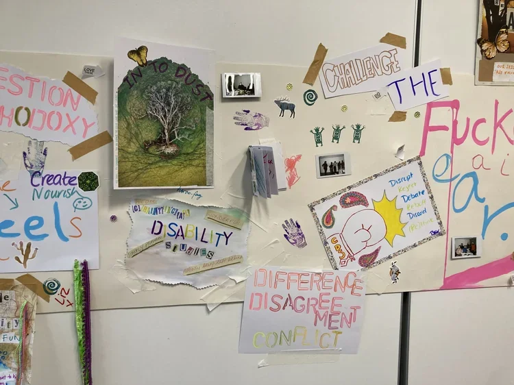A colorful collage of various handmade signs, drawings, and photos taped to a white wall, featuring messages about emotions, disability, conflict, and personal topics.